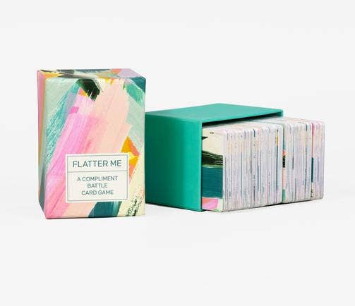 Flatter Me: A Compliment Battle Card Game box with cards partially visible.