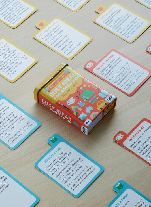 Busy Ideas for Bored Kids: Rainy Day Edition box with activity cards displayed on a wooden table.