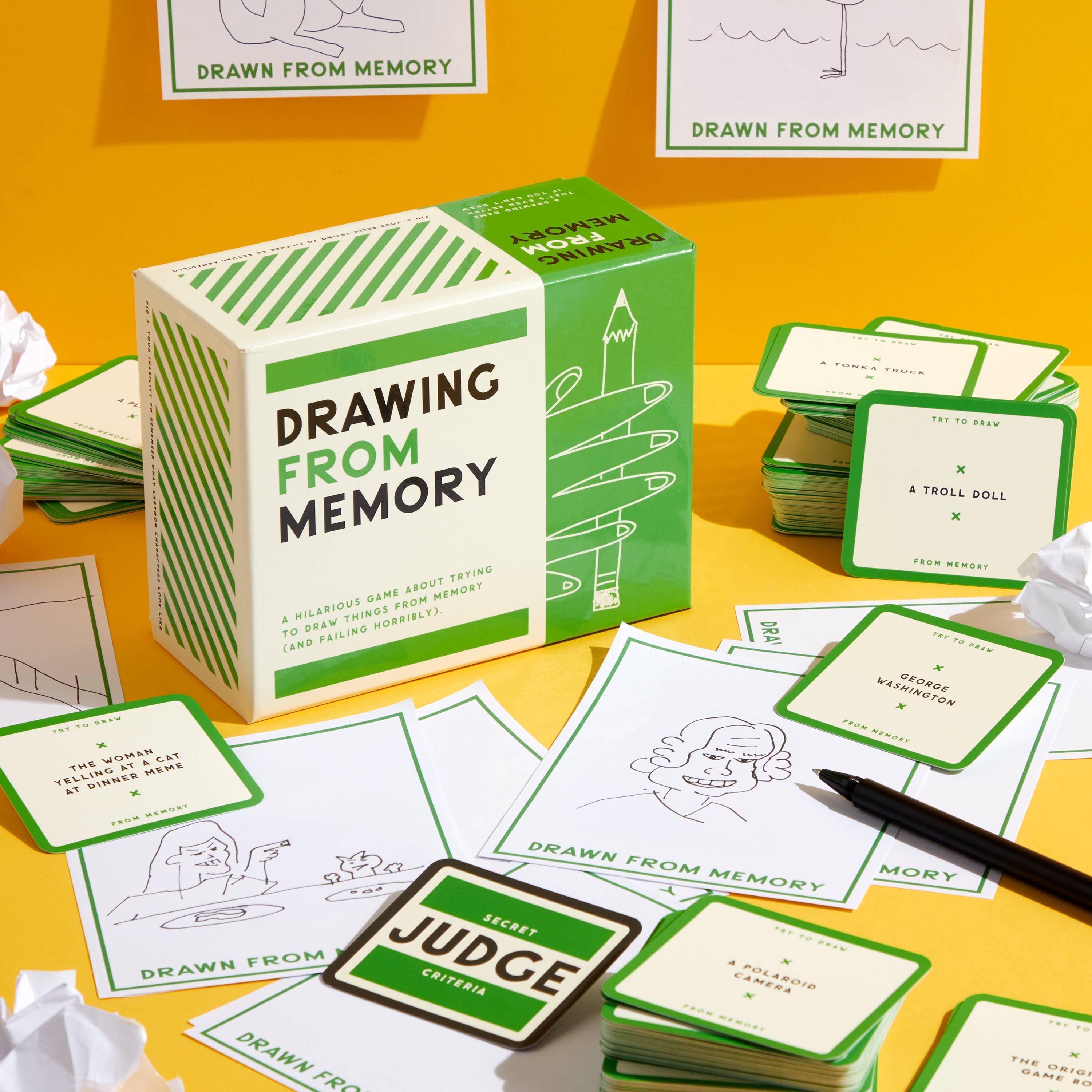 Brass Monkey Drawing From Memory Game including box, cards, and crumpled paper on a yellow surface.
