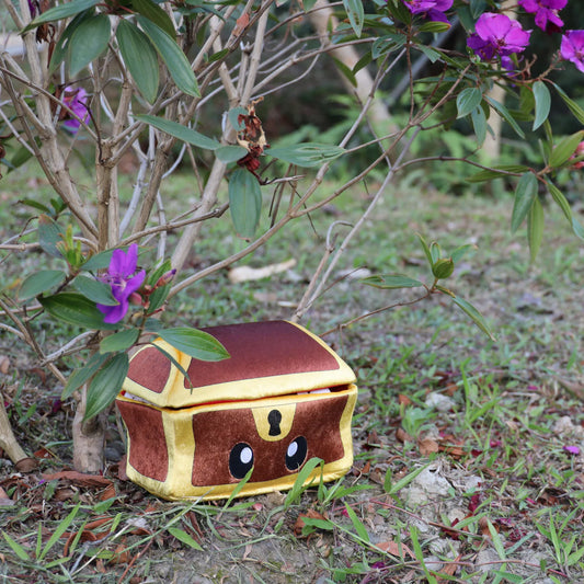 Mimic Plush by Tentacle Kitty, 8-inch, with cartoon eyes positioned on grass under a bush with purple flowers.