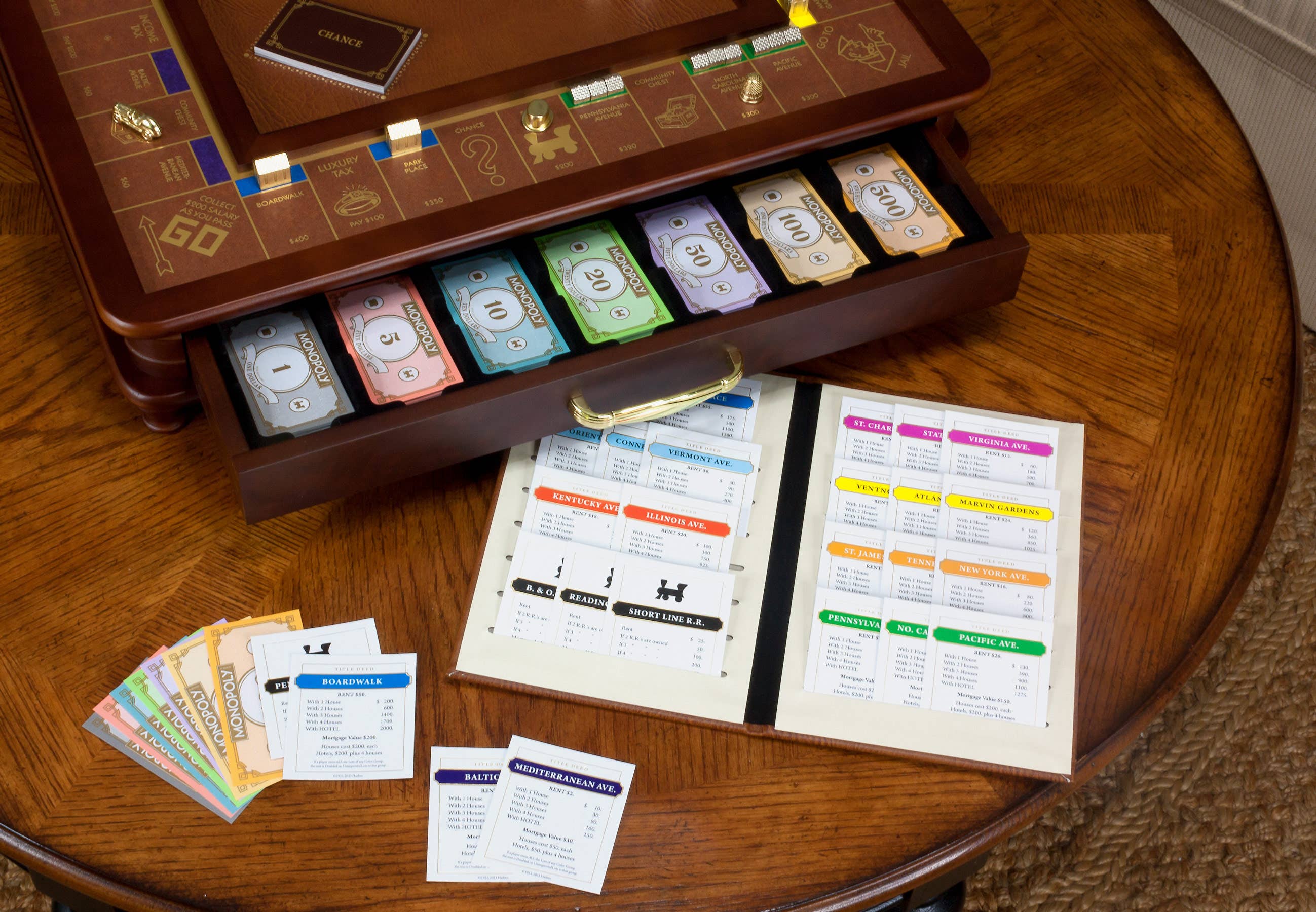 Monopoly Luxury Edition set with organized money, property cards, and an open booklet on a wooden table.