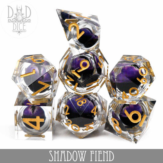 Shadow Fiend - Liquid Core: Set of seven clear resin dice with gold numbers and black-purple centers.