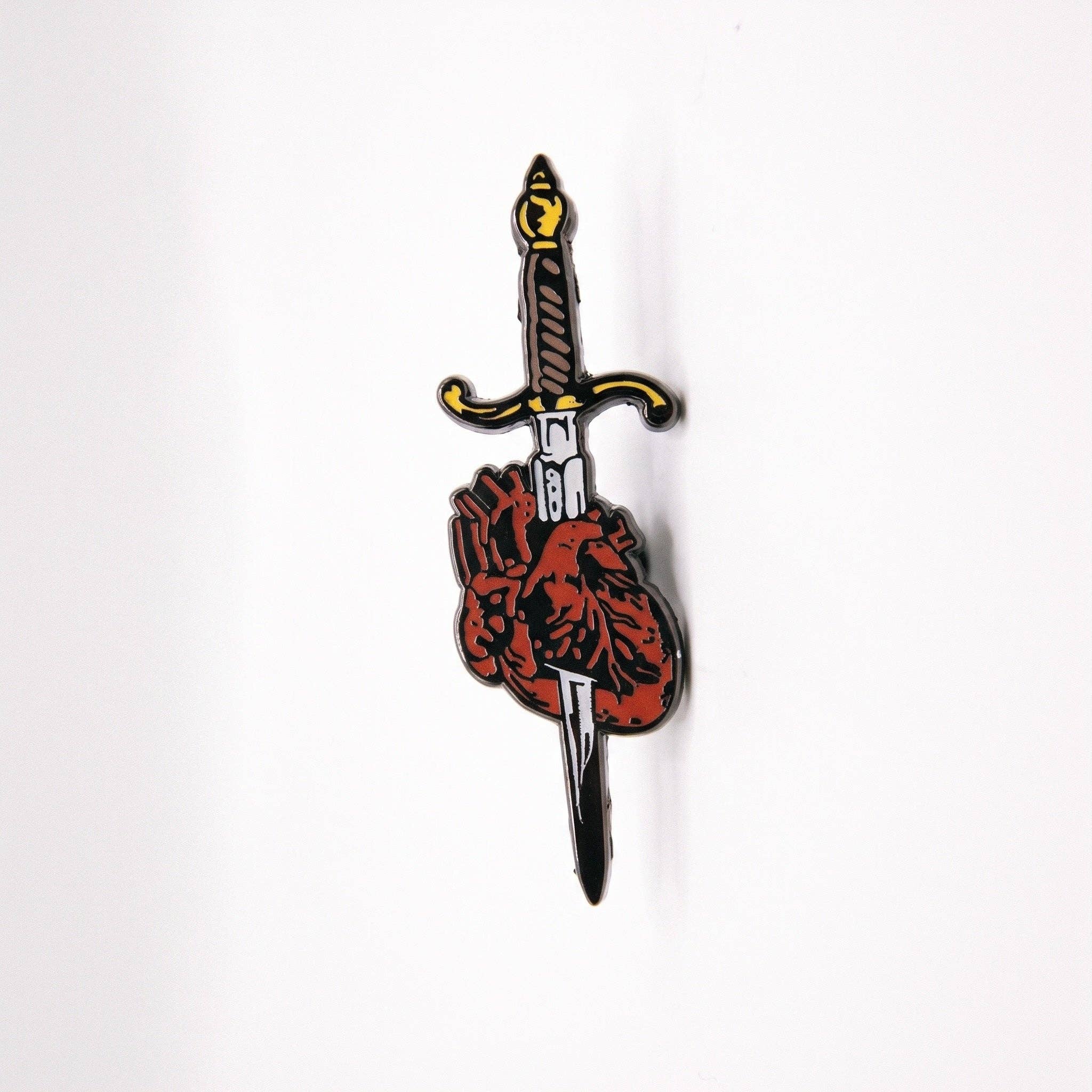 Stabbed Heart pin: black plated enamel sword piercing an anatomical red heart with a locking clasp.