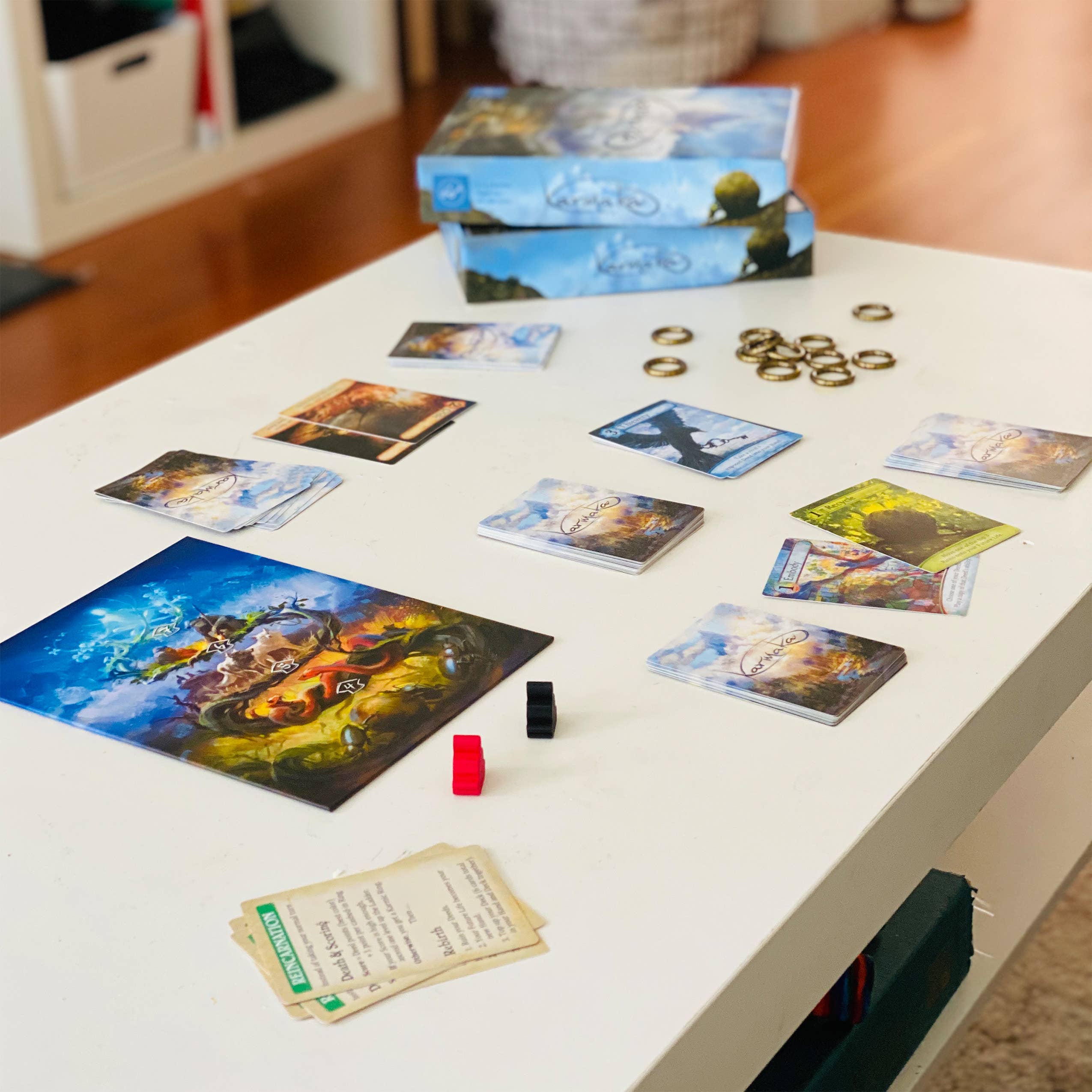 Karmaka card game components including cards and tokens arranged on a table.