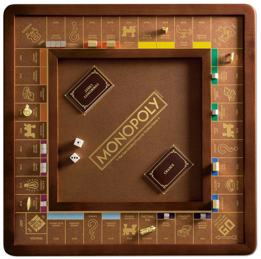 Monopoly Luxury Edition with gold details, cards, dice, and collectible pieces on a brown surface.