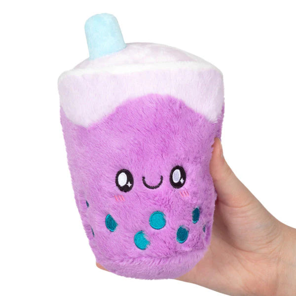 Snugglemi Snackers Bubble Tea Squishable plush, purple with teal boba pearls and a smiling face, held in one hand.