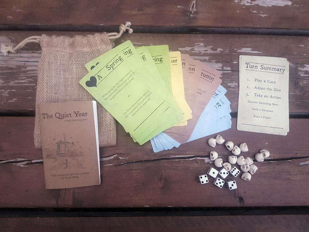 The Quiet Year updated bag set with cards, dice, skull tokens, burlap bag, and rulebook.