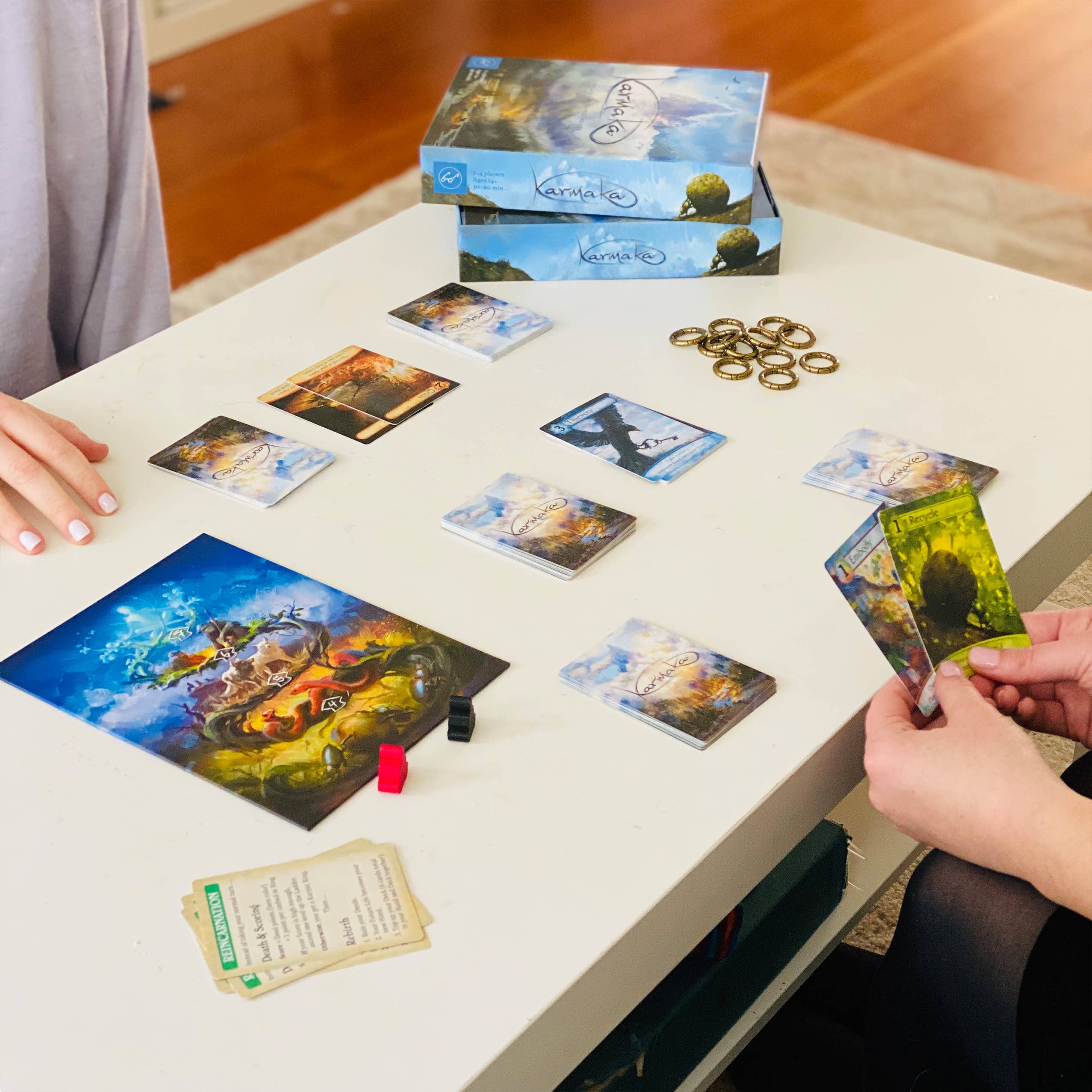 Karmaka card game set with board, tokens, and two players.