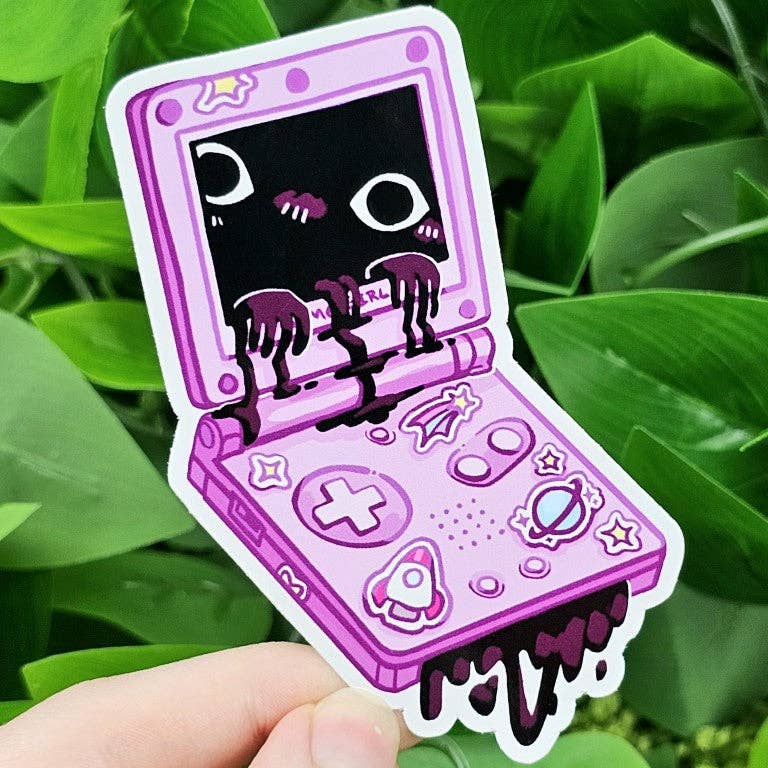 Creepy Game Console Sticker featuring black goo and eyes on screen, held in a hand.