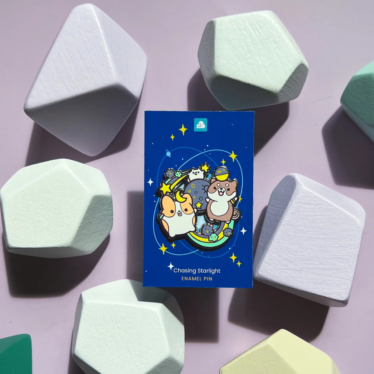 Chasing Starlight Enamel Pin on a card with cartoon animals and stars on a blue background.