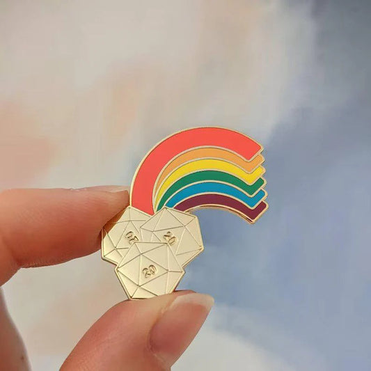 End of the Rainbow Hard Enamel Pin featuring a rainbow above three gold 20-sided dice, held in a hand.