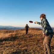 Two people tossing an Indoor MayaFlya (Pocket Disc) outside.