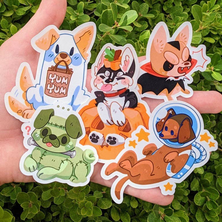 Six Halloween Puppies Stickers featuring puppies in costumes held in a hand.