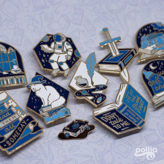 Booxcalibur Pin in blue, white, and gold enamel with book, RPG, astronaut, and fantasy motifs.