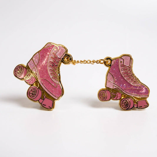 Two pink glittery roller skate hard enamel pins connected by a gold-plated chain.