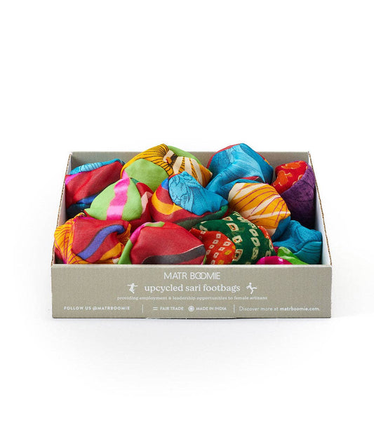 Box containing handmade Sari Footbag Hacky Sacks crafted from upcycled saris with varied vibrant patterns.