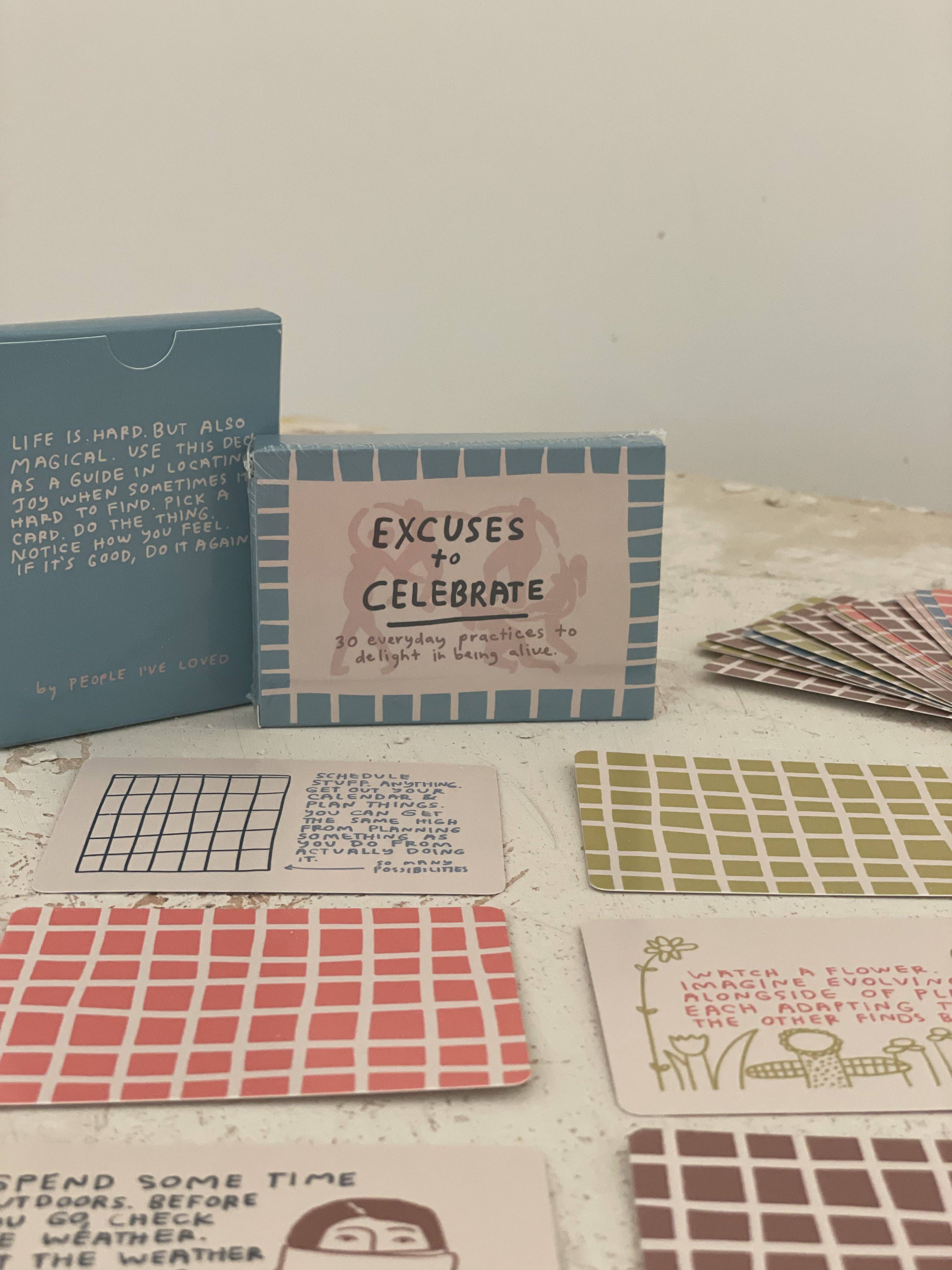 Excuses To Celebrate Deck with illustrated cards displayed on a table.