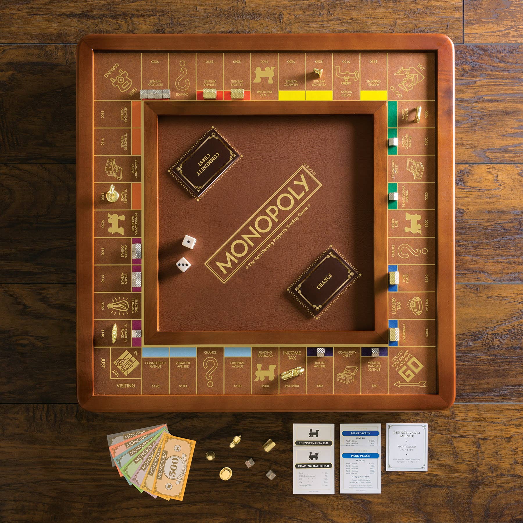 Monopoly Luxury Edition set with cards, dice, money, and playing pieces displayed on a wooden table.