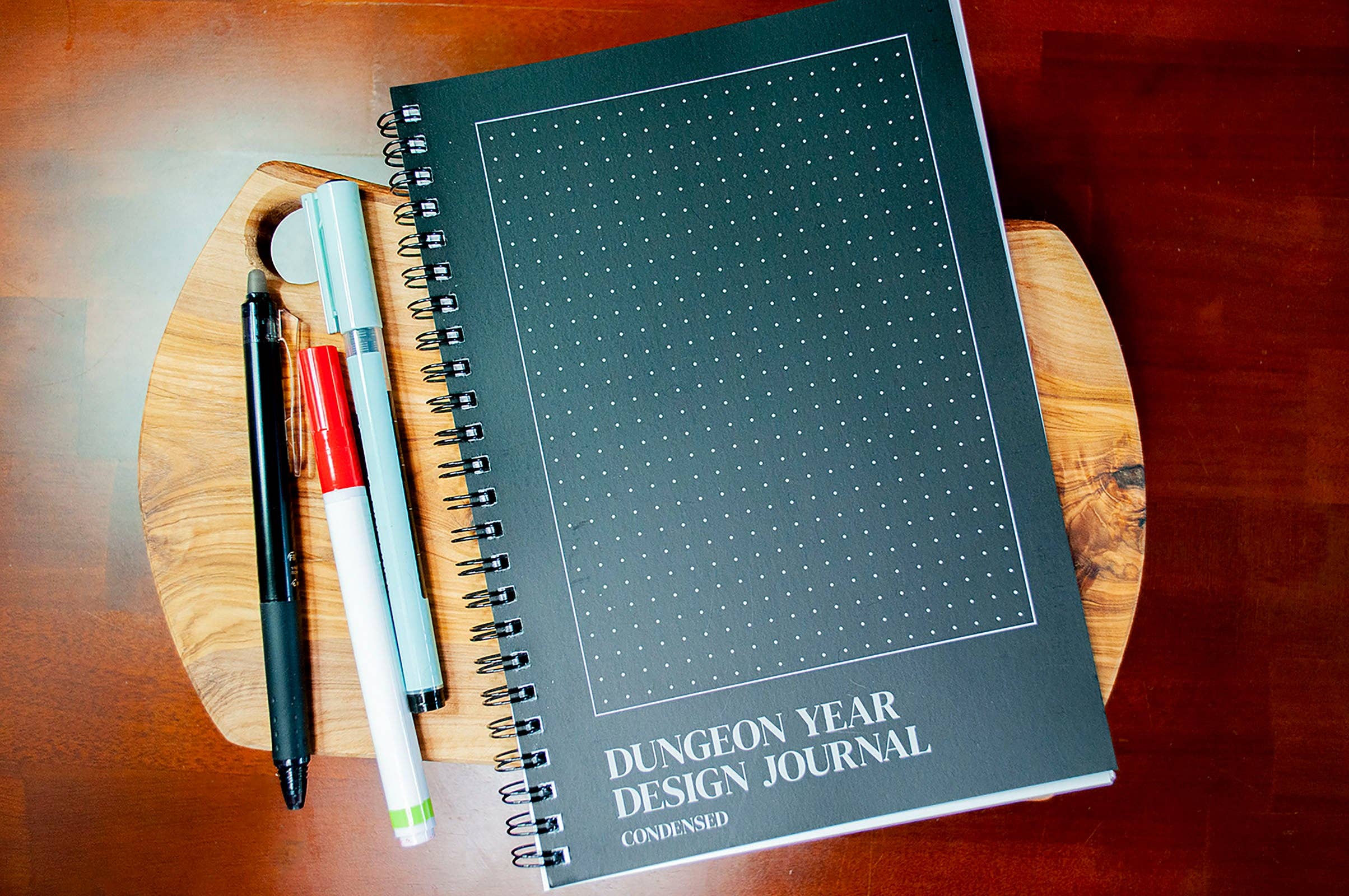 Dungeon Year Design Journal with pens and a marker.
