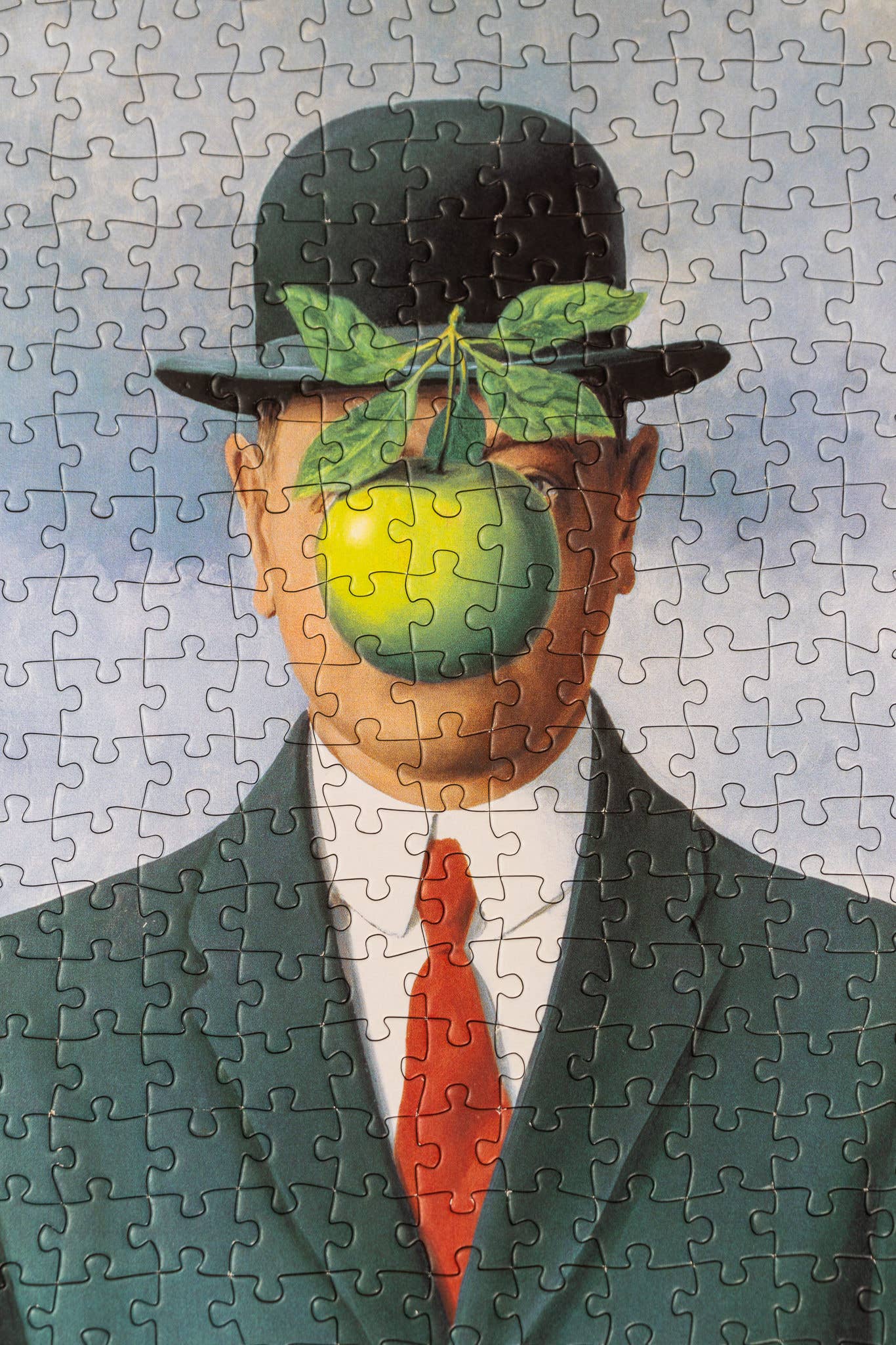 René Magritte Son of Man 1000-piece puzzle featuring man in suit, bowler hat, and green apple covering his face.