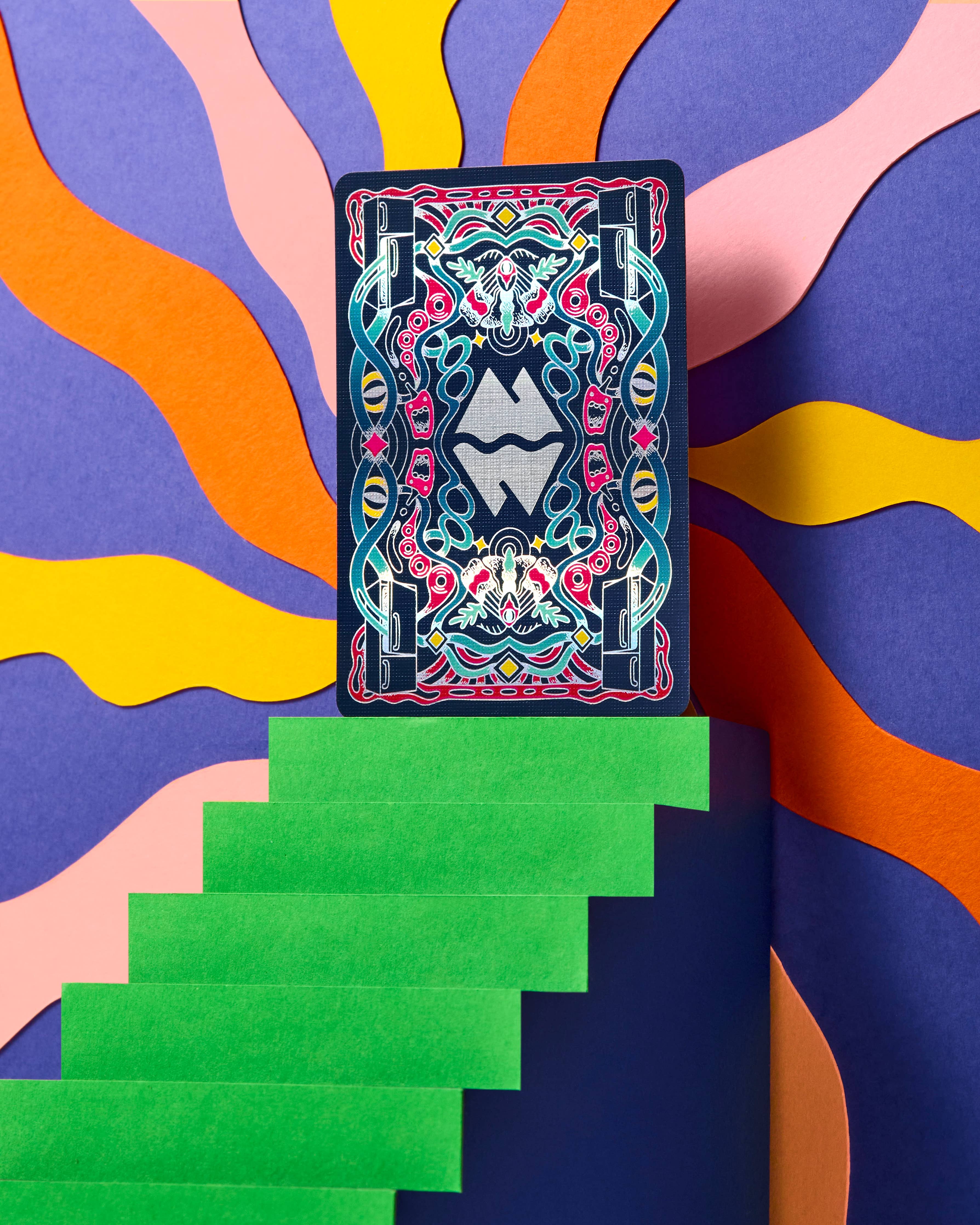 Meow Wolf playing card with a blue holographic back and symmetrical neon geometric pattern.