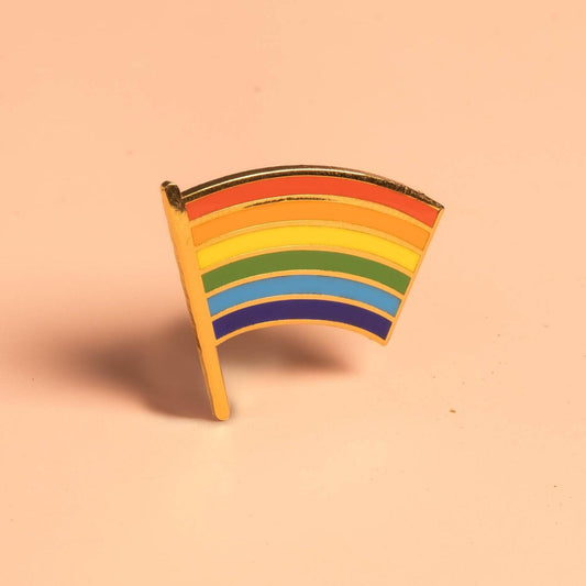 Pride Flag Pin featuring a rainbow flag design on a peach background.