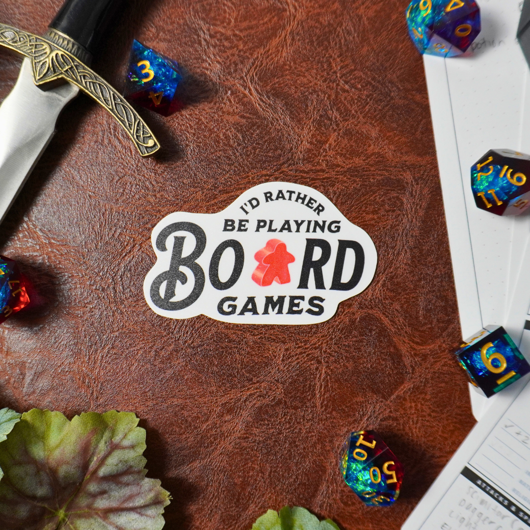 Sticker with text: Id Rather Be Playing Board Games—references dice, paper, and leather-surface gaming.