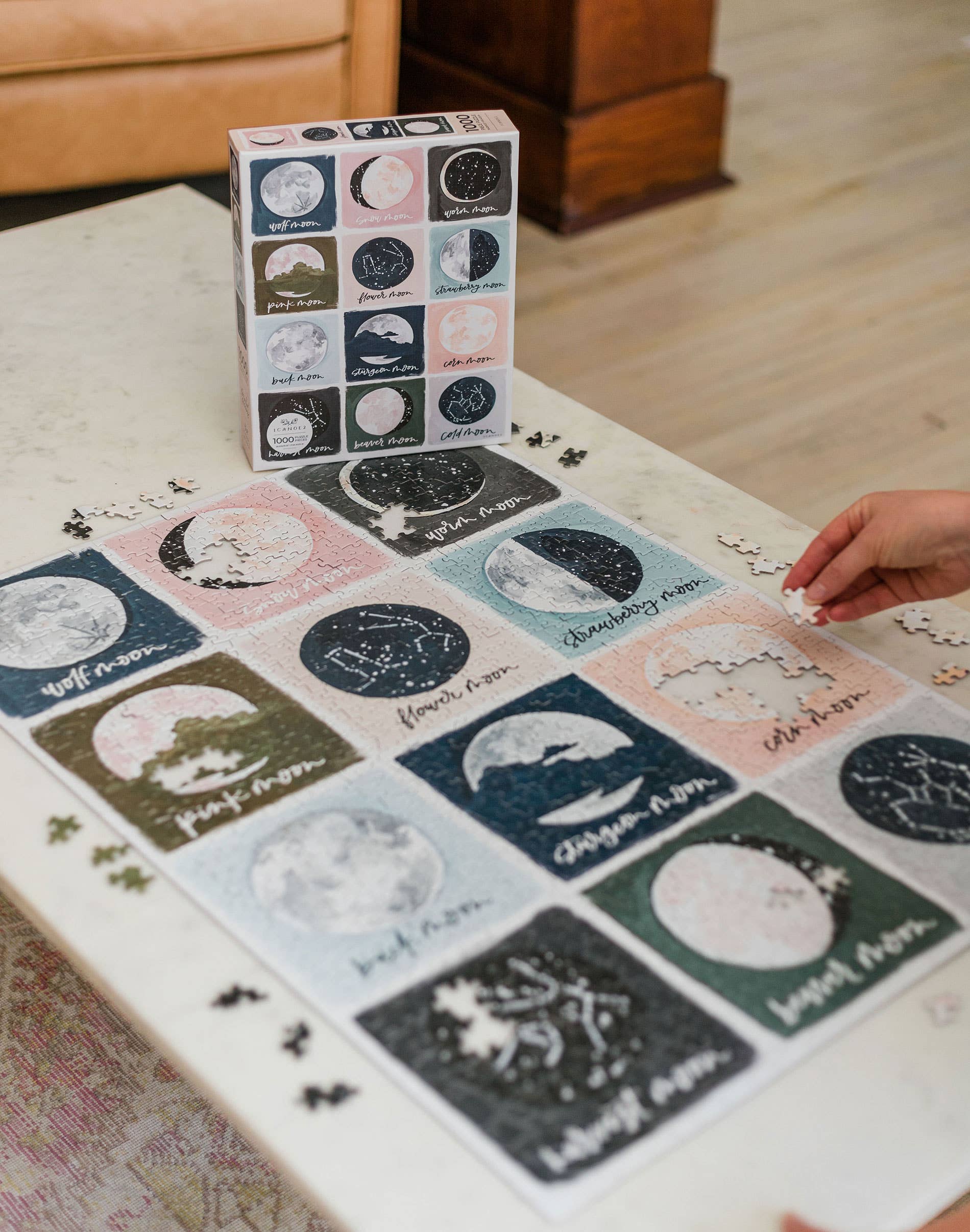 Painted Moons 1,000 Piece Jigsaw Puzzle with moon phase pieces being assembled on a table.