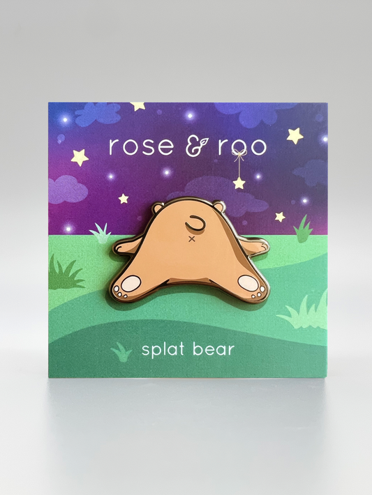Splat Bear enamel pin on backing card labeled rose & roo with night sky background.