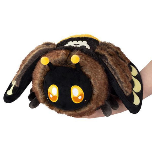 Mini Deaths-Head Hawkmoth plush with big yellow eyes and small wings held by a hand with red hair.