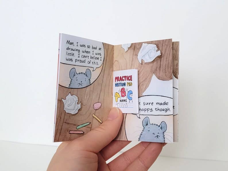 A hand holds The Chinchillustrator Mini-Comic Zine.