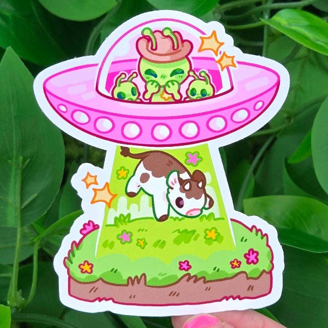 Cowboy Alien sticker sheet featuring a pink UFO beaming up a cow over grass and green leaves.