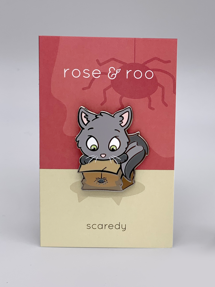 Scaredy enamel pin showing a cartoon gray cat peeking into a box with a spider. Card reads “rose & roo” and “scaredy.”.
