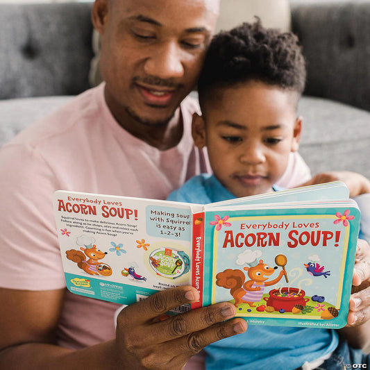 Everybody Loves Acorn Soup toddler board book held by an adult and child sitting on a couch.