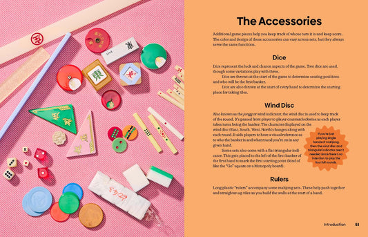 Mahjong set with colorful dice, rulers, game pieces, and a how-to guide on a pink background.