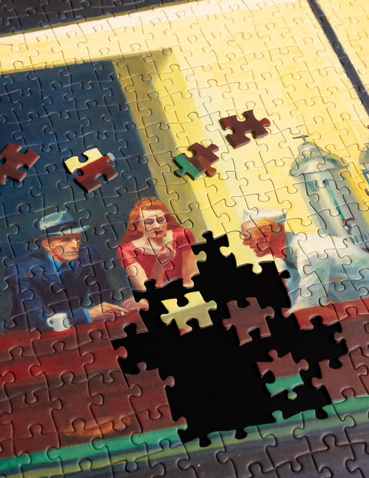 1000-piece Edward Hopper Nighthawks puzzle with center and top pieces missing, showing people at a counter.