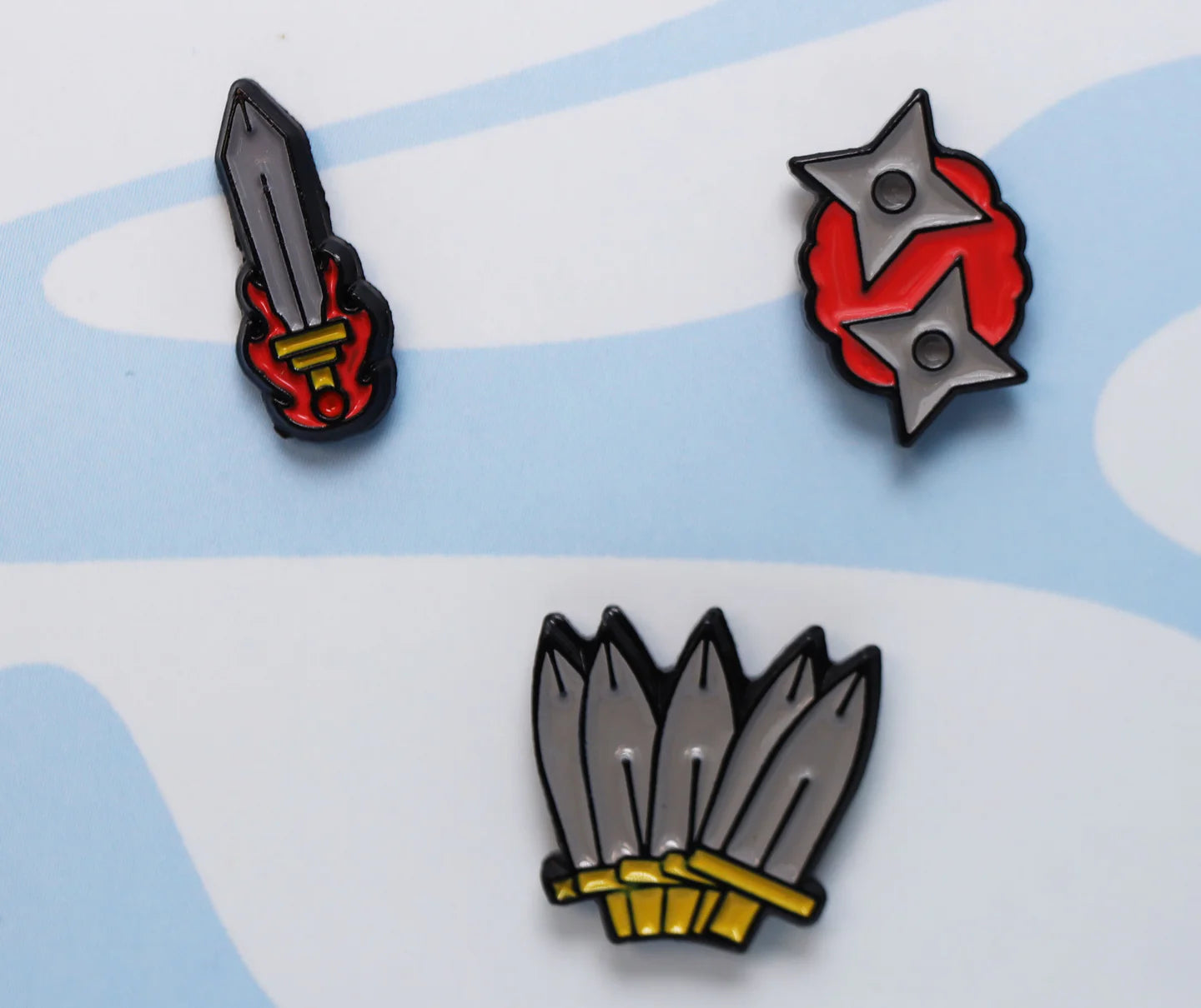 The Mini Pins: Weapons Pack with a flaming sword, red shuriken, and five kunai knives.