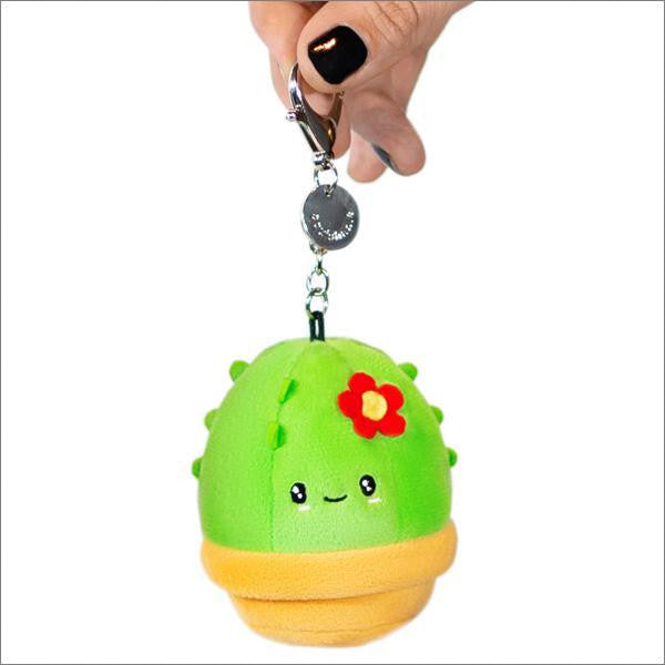 Micro Cactus keychain with a smiling face, red flower, and yellow pot held in a hand.