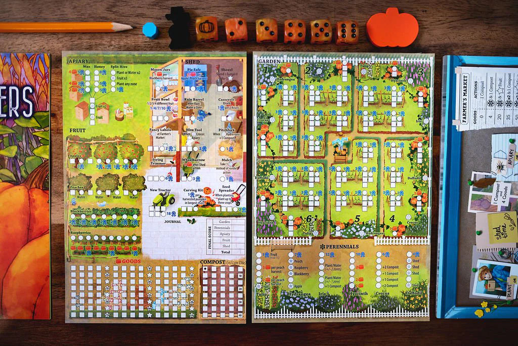 Three Sisters board game components: score sheets, dice, pencil, and orange pumpkin token arranged on a table.