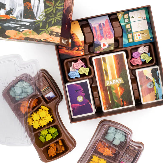 PARKS board game with open box showing organized trays holding cards, colorful tokens, and hiking pieces.