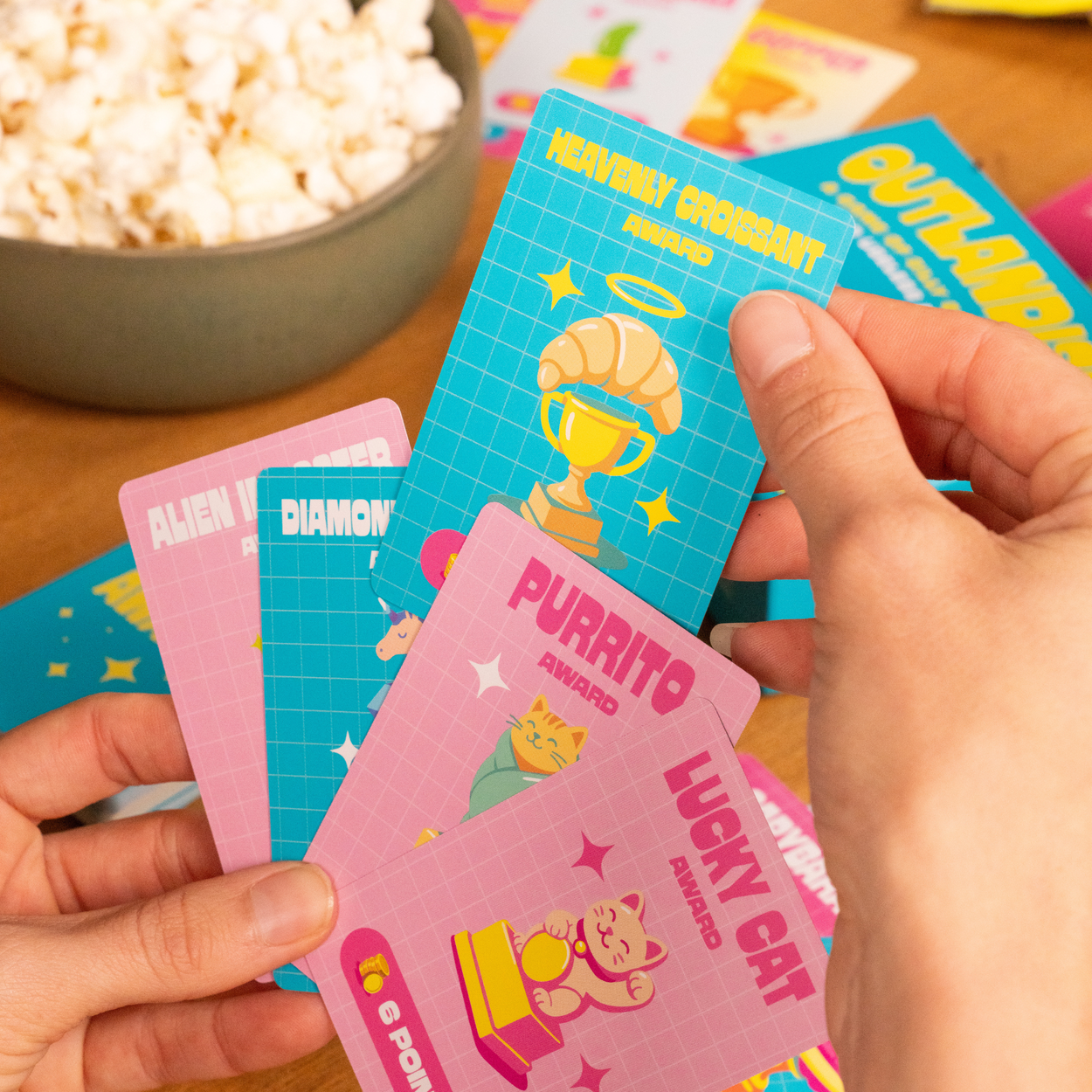 Outlandish party game with question cards and colorful award cards, includes playful illustrations on components.