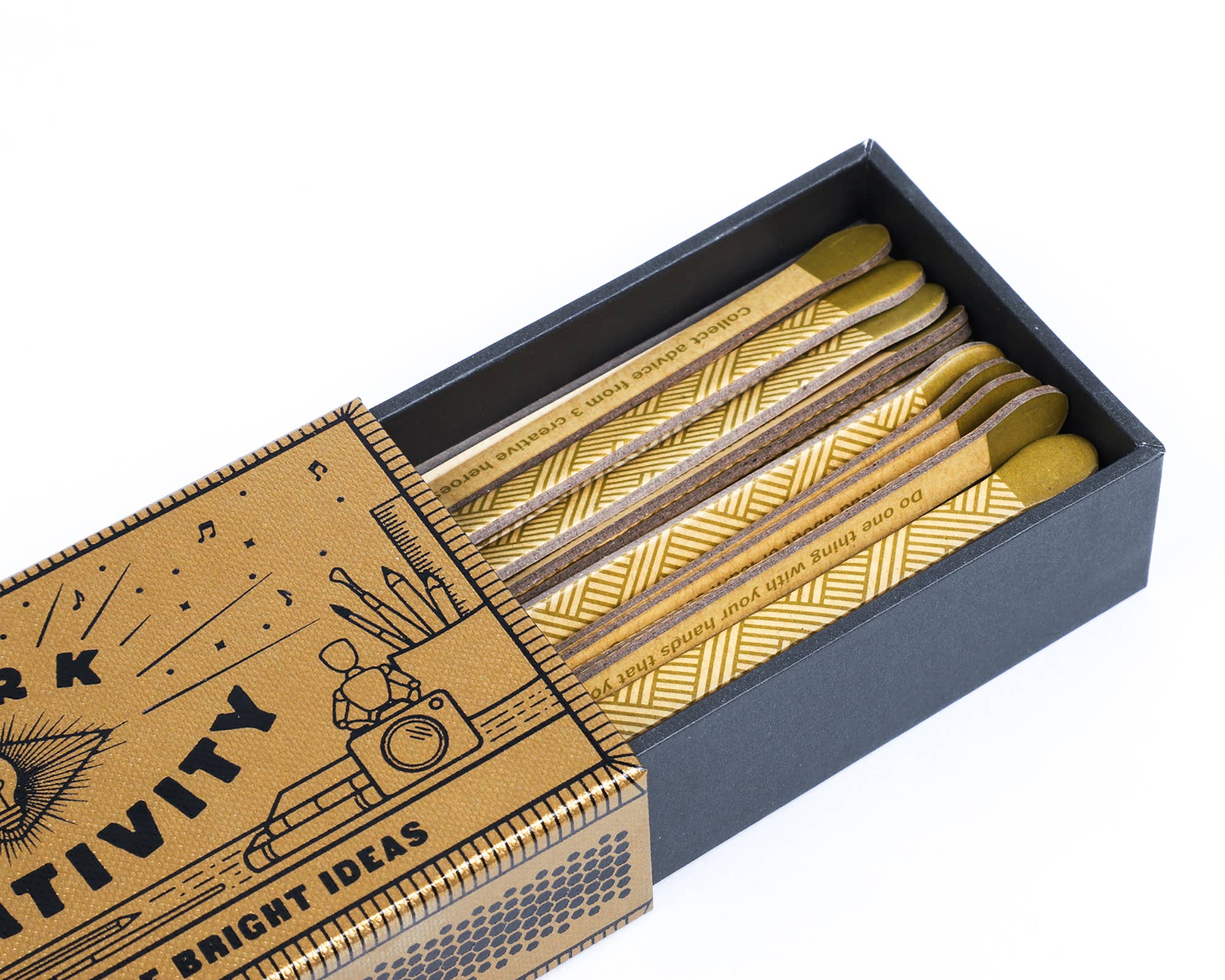 Spark Creativity matchbox with gold pattern, some matches featuring prompts, colorful matchsticks inside.