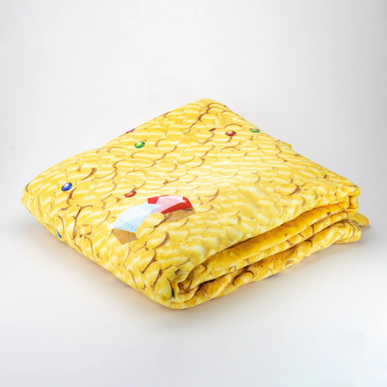 Folded Treasure Hoard Blanket by Tentacle Kitty with corn kernel pattern and scattered small colorful objects.