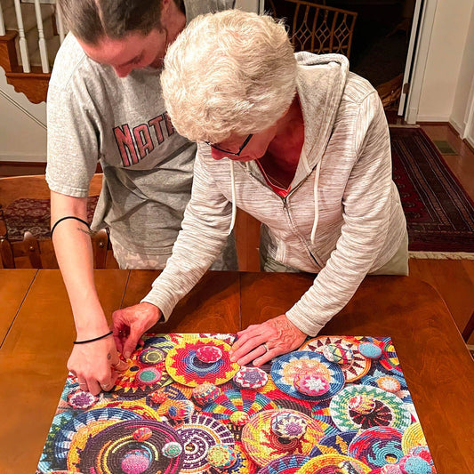 Limited Edition Buena Onda Games Puzzle with colorful circular patterns being assembled by two people on a table.