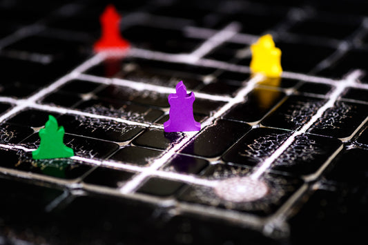 The Night Cage: Spooky Cooperative Strategy Game board with white grid lines, paths, and colorful playing pieces.