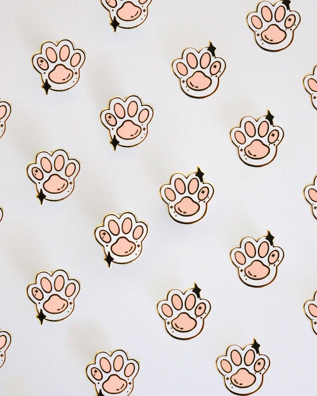 Toe Beans Enamel Pins with gold outlines in a pink cat paw design on a white background.