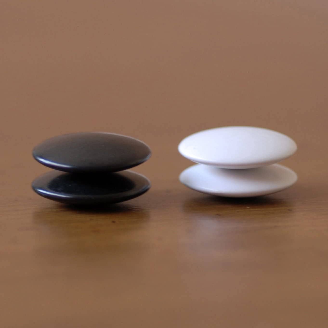 Wooden GO Game - 12 Inch, two round magnets placed side by side on a wood veneer surface.