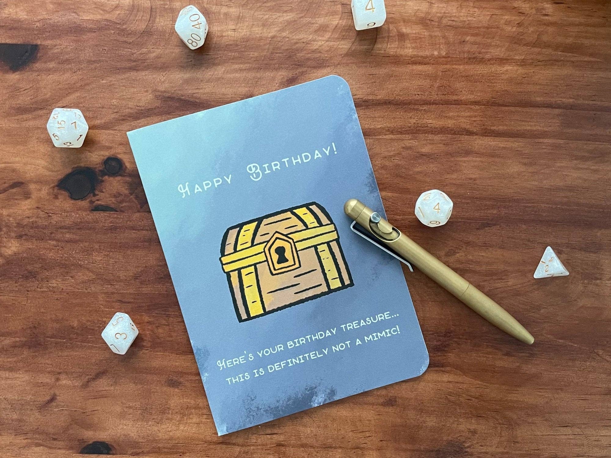 Not A Mimic Birthday Card featuring a treasure chest, dice, pen, and Happy Birthday text.