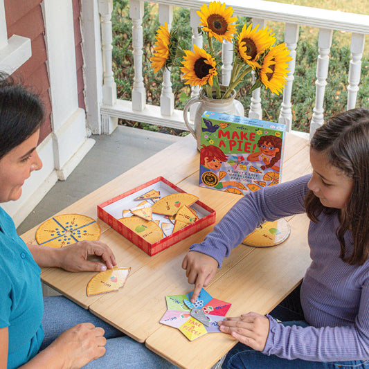 Make a Pie Game being played by a woman and girl at a table. Sunflowers in vase visible in background.