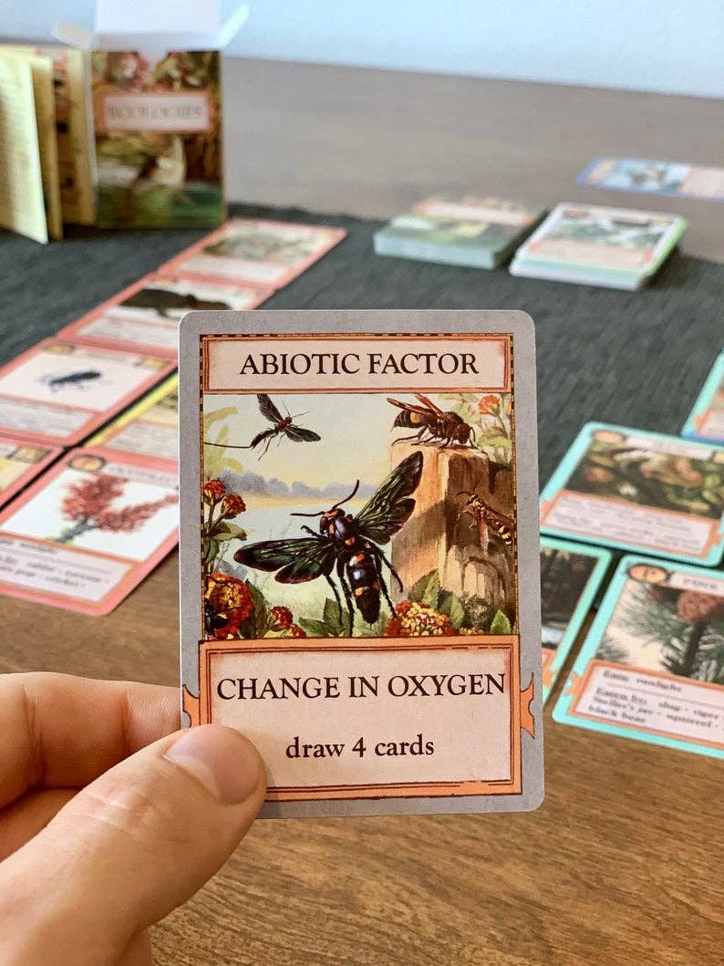 Ecologies Card Game card held in hand: Abiotic Factor: Change in Oxygen with insects, text reads Draw 4 cards.